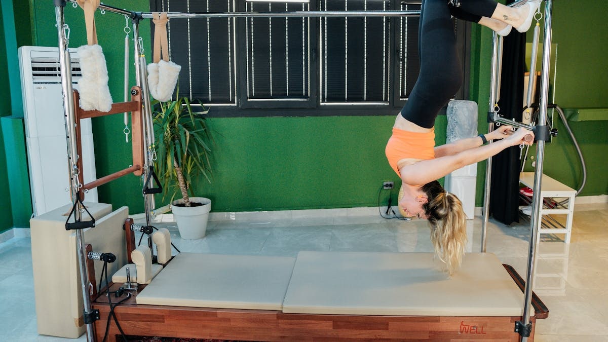 Woman practicing reformer pilates exercise in a modern fitness studio